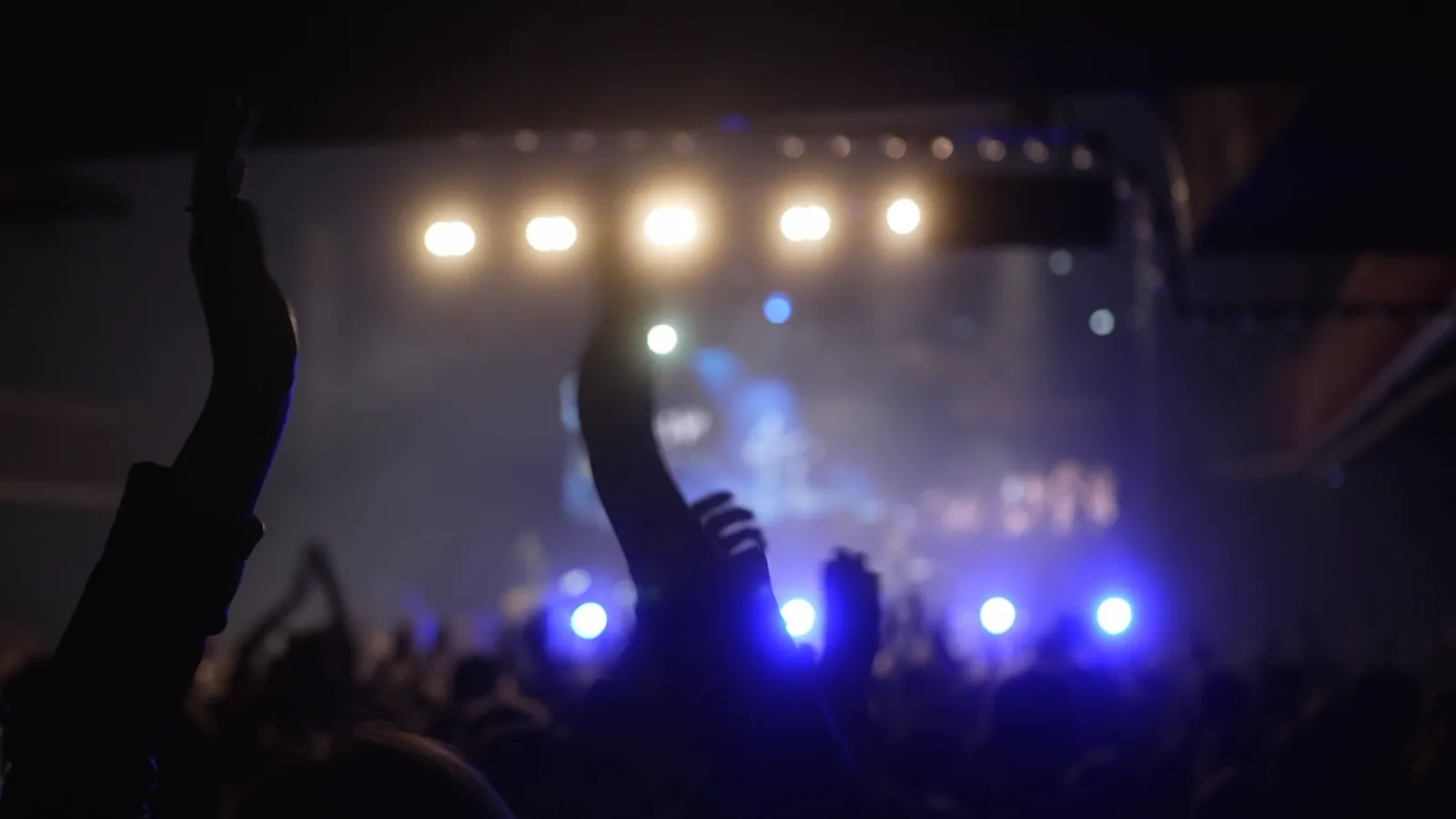 A concert crowd inside Toyota Arena, hands up toward the stage lights